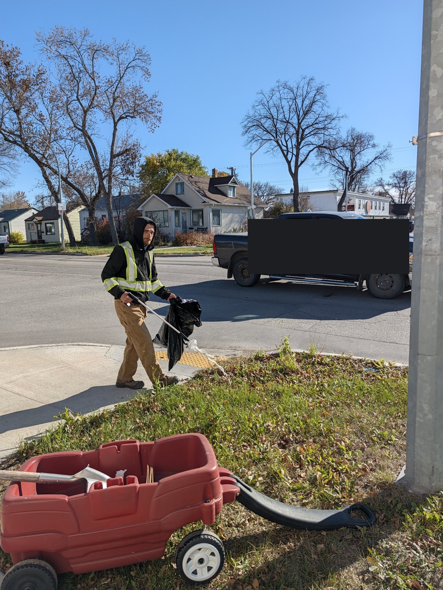 Nicholas holding a litter grabber and bag during the Transcona community cleanup